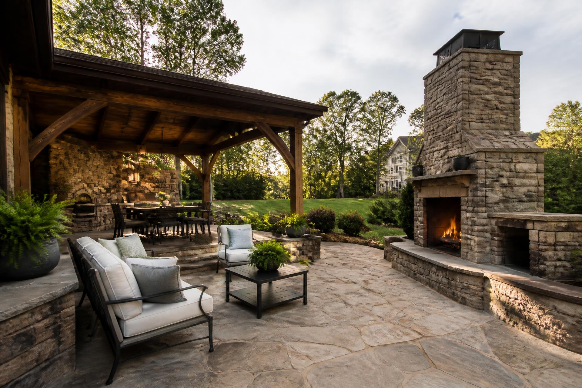Luxury outdoor living space with stone fireplace and outdoor kitchen at dusk
